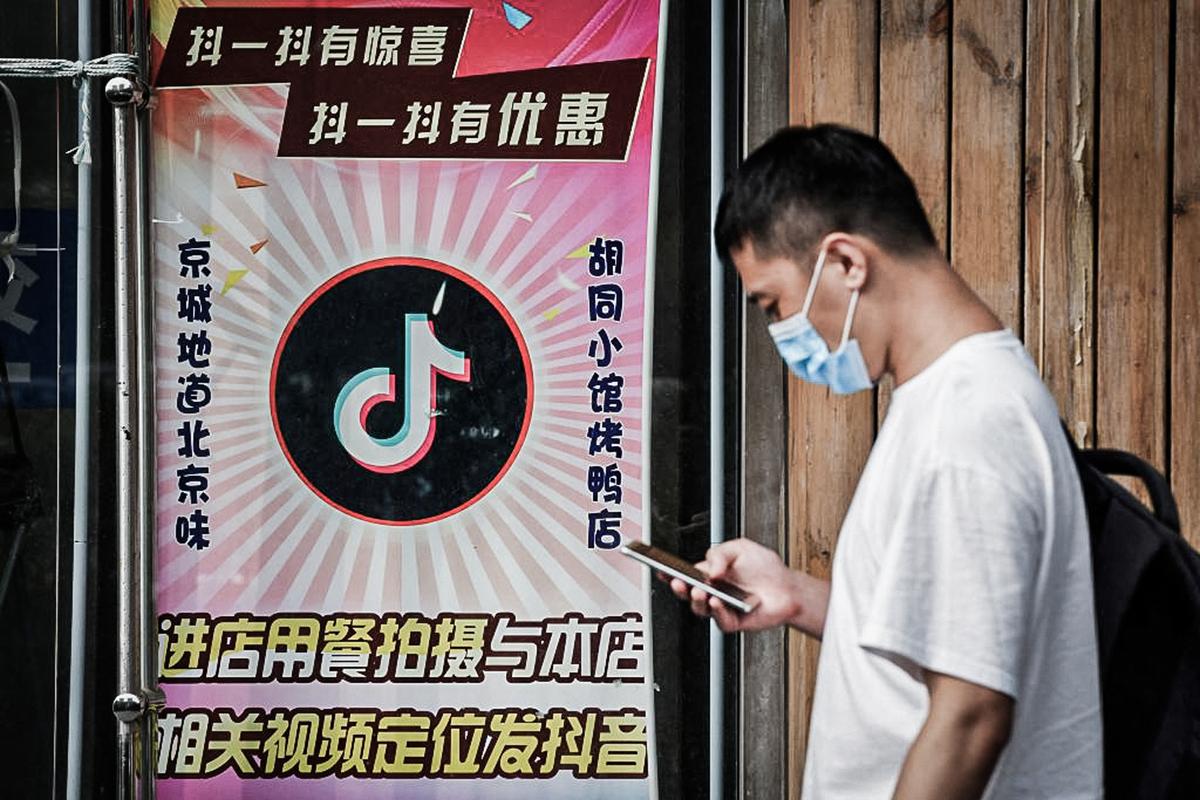 A man walks past a restaurant with a TikTok logo displayed in the window in Beijing on Sept. 14, 2020. (Greg Baker/AFP via Getty Images)