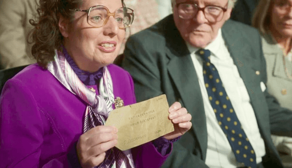 Audience Member (Valerie Hazan) holds her verification papers, unknowingly sitting next to the man who saved her, Nicholas Winton (Anthony Hopkins), in "One Life." (Warner Bros.)