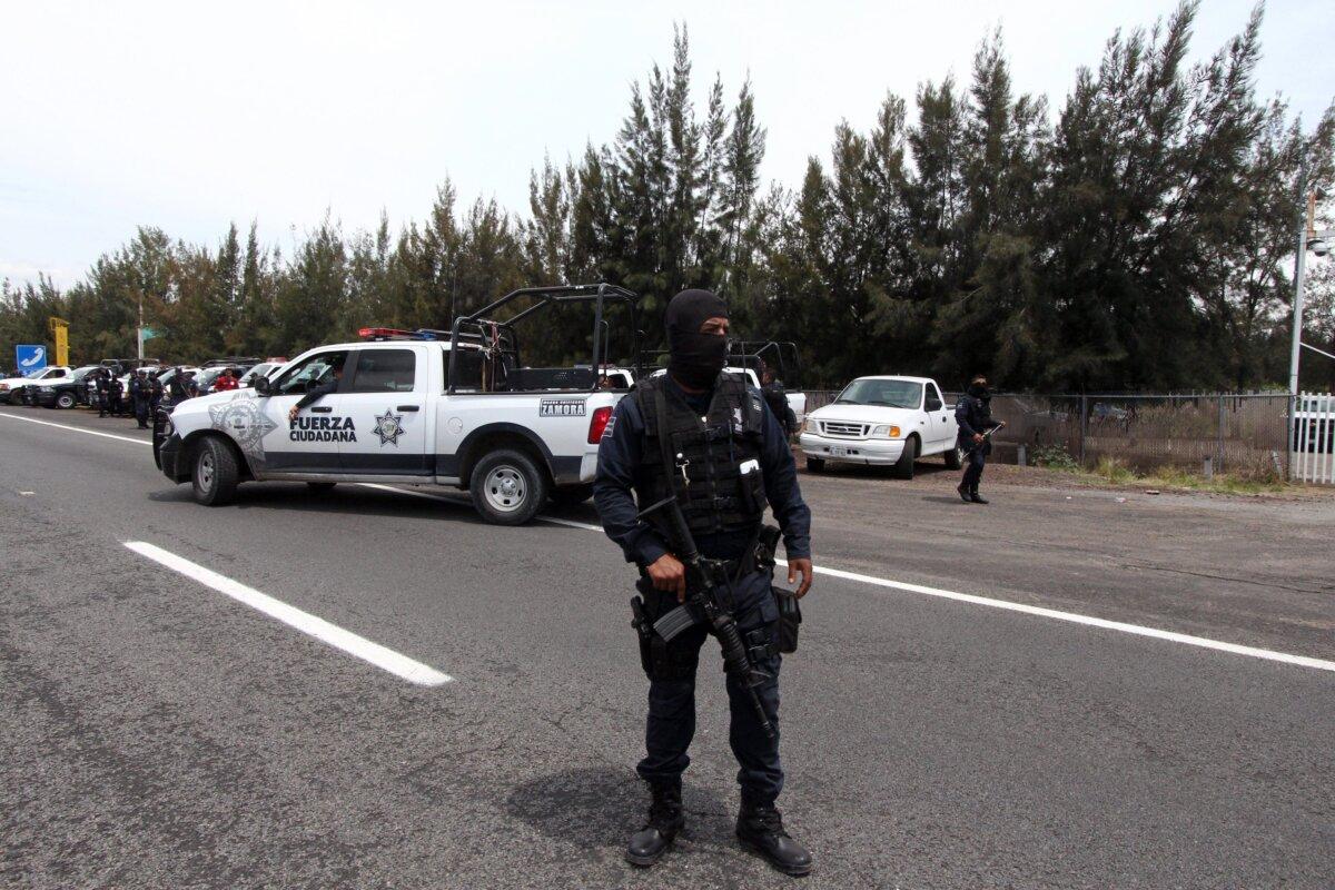 Federal police officers stands guard outside the ranch where gunmen took cover during an intense gun battle with the police, along the Jalisco-Michoacan highway in Vista Hermosa, Michoacan State, Mexico, on May 22, 2015. (Hector Guerrero/AFP via Getty Images)