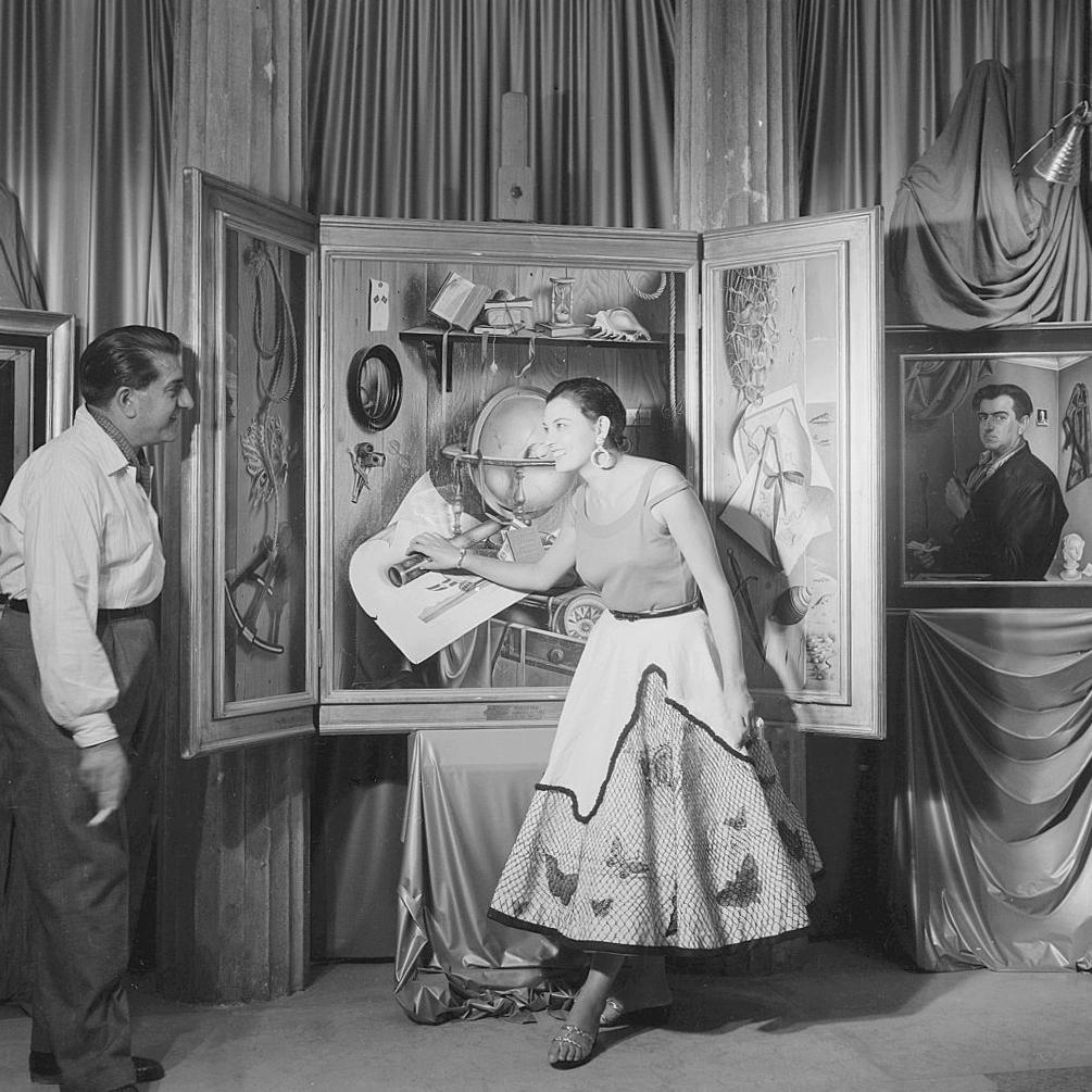 Armenian painter Gregorio Sciltian and his wife Elena Boberman, who stands in front of one of his “trompe l’oeil” (deceives the eye) paintings, at the 16th Venice International Film Festival, in 1955. (Public Domain)