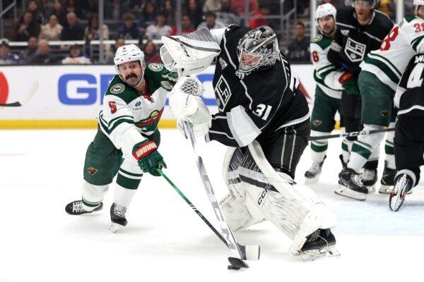 Jake Middleton (5) of the Minnesota Wild battles David Rittich (31) of the Los Angeles Kings for a loose puck during the first period of a game in Los Angeles on March 20, 2024. (Sean M. Haffey/Getty Images)