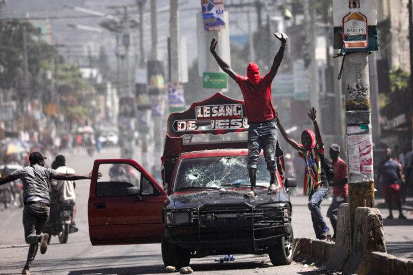 A man with his face covered calls on demonstrators to stop during a protest against Prime Minister Ariel Henry's government in Port-au-Prince, Haiti, on March 1, 2024. (Ralph Tedy Erol/Reuters)