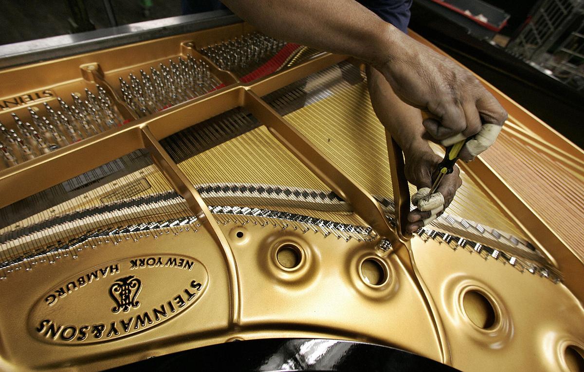 A worker strings the soundboard of a Concert Grand Model D Piano at the Steinway & Sons factory in Long Island City, New York. (Timothy A. Clary/Getty Images)