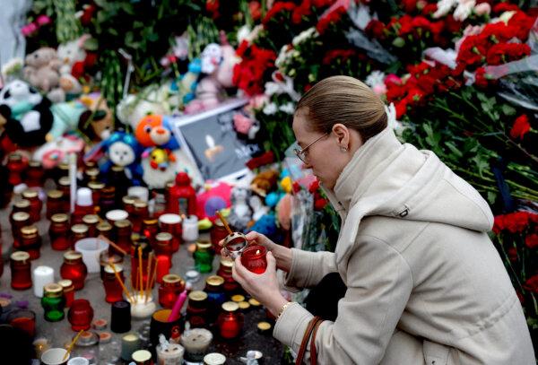 A woman lights a candle at a memorial to the victims of a March 22, 2024, shooting attack at the Crocus City Hall concert venue in Moscow, on March 24, 2024. (Maxim Shemetov/Reuters)
