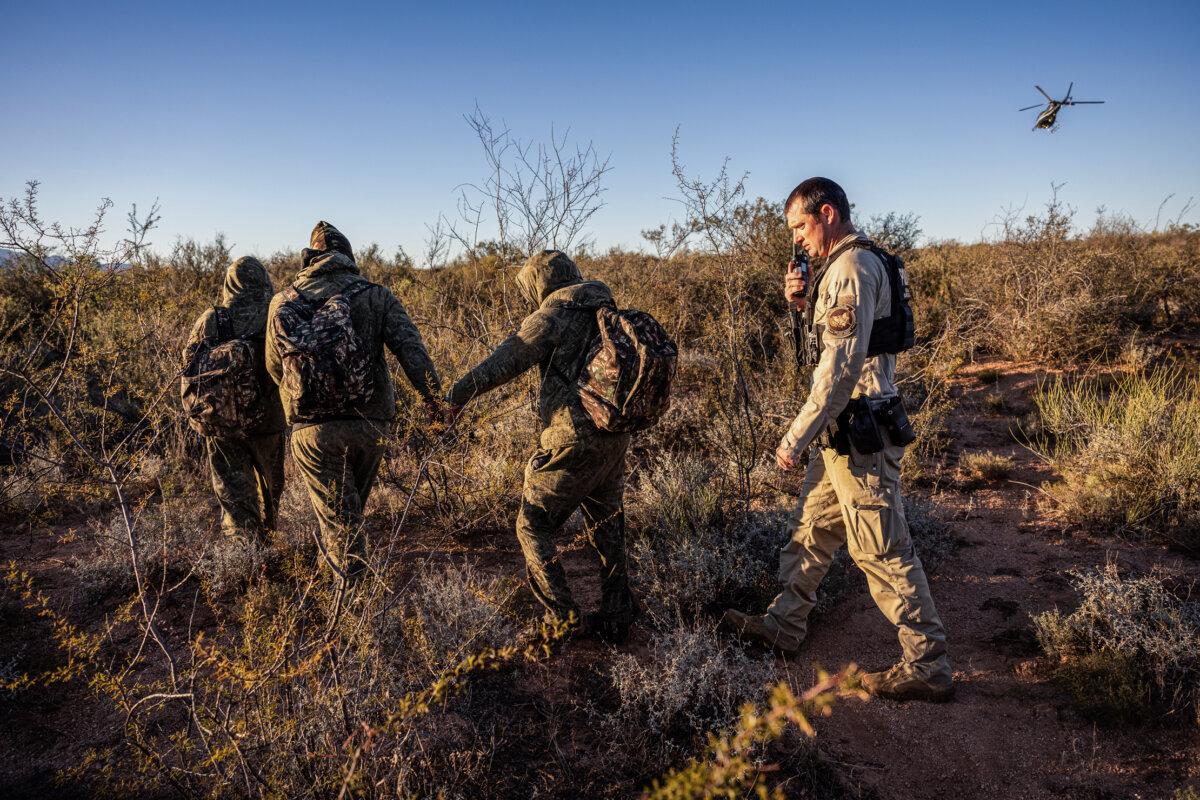 A border agent detains camouflaged Mexican nationals who illegally entered the United States near Naco, Ariz,. on Nov. 4, 2022. (John Moore/Getty Images)