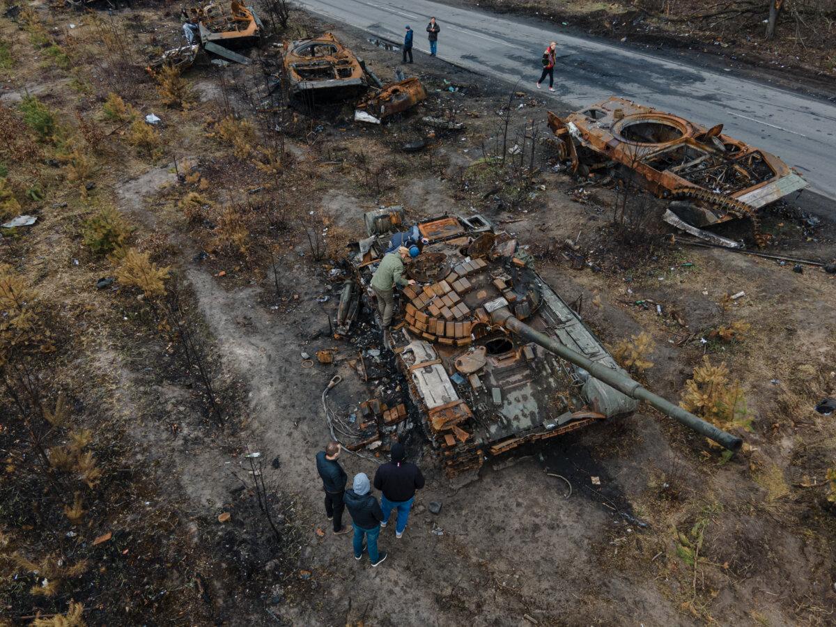 In this aerial image, people inspect destroyed Russian military vehicles by the side of a road in Dmytrivka, Ukraine, on April 21, 2022. (Alexey Furman/Getty Images)