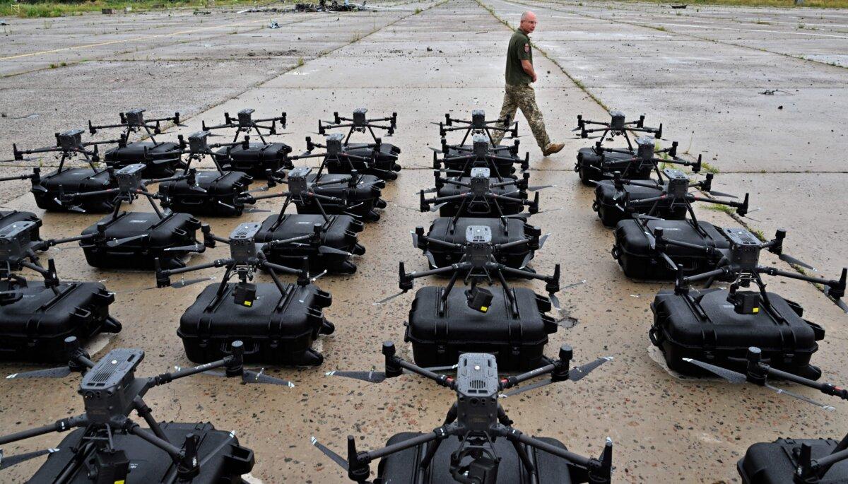 A military operator walks past DJI Matrice 300 reconnaissance drones, bought in the frame of the program "The Army of Drones," set up and ready for test flights before being sent to the front line in the Kyiv region of Ukraine on Aug. 2, 2022. (Sergei Supinsky/AFP via Getty Images)