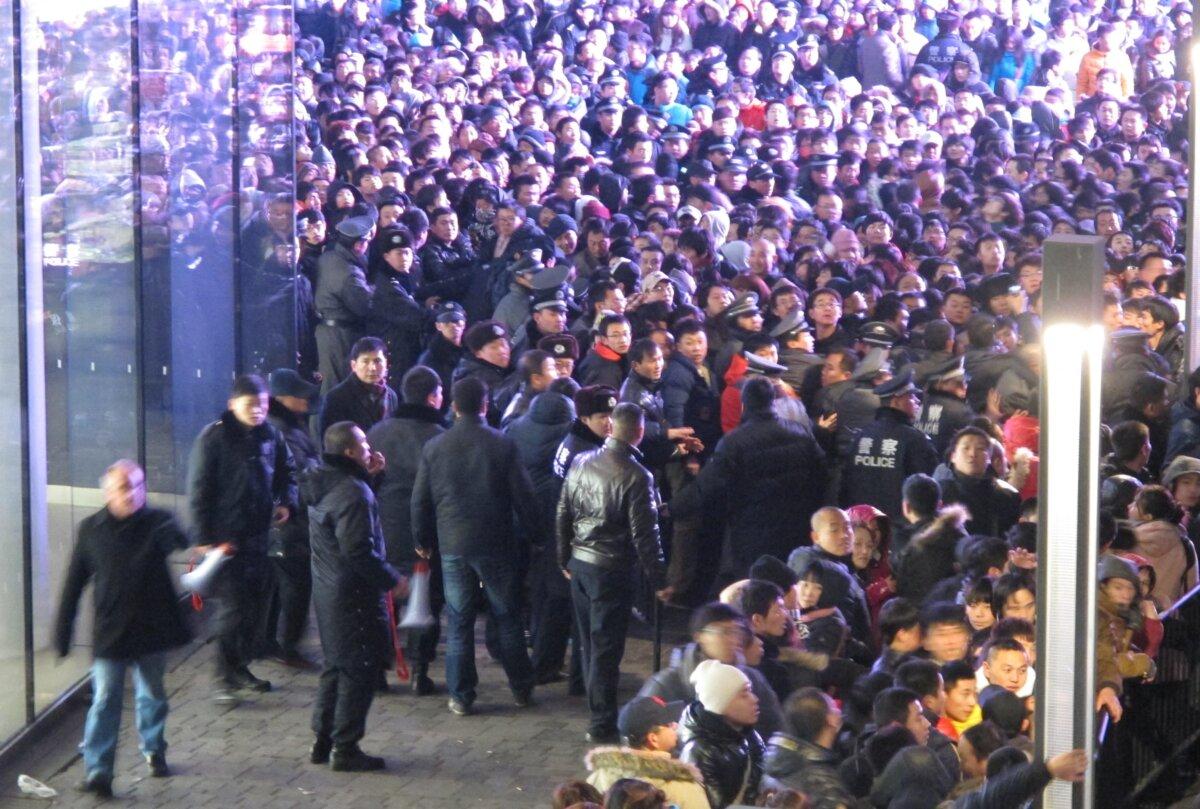 Police try to seal off the area as thousands of customers queue up outside an Apple store in Beijing's upmarket Sanlitun shopping district, in Beijing early morning on Jan. 13, 2012. (AFP via Getty Images)