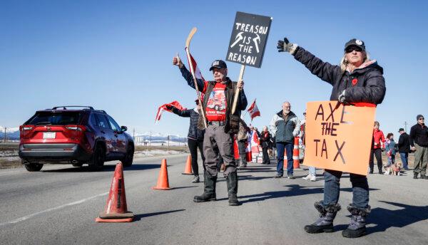 Anti-carbon tax protesters wave signs and chant slogans as they block a westbound lane of the Trans Canada highway near Cochrane, Alta., on April 1, 2024. (Jeff McIntosh/The Canadian Press)