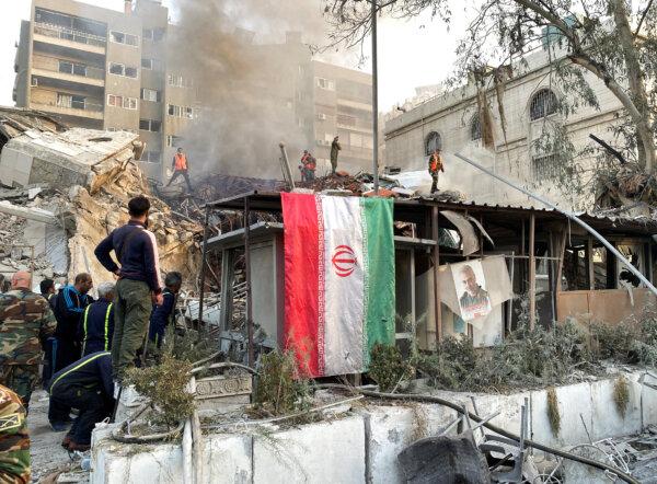 An Iranian flag hangs as smoke rises after what the Iranian media said was an Israeli strike on a building close to the Iranian Embassy in Damascus, Syria, on April 1, 2024. (Firas Makdesi/REUTERS)