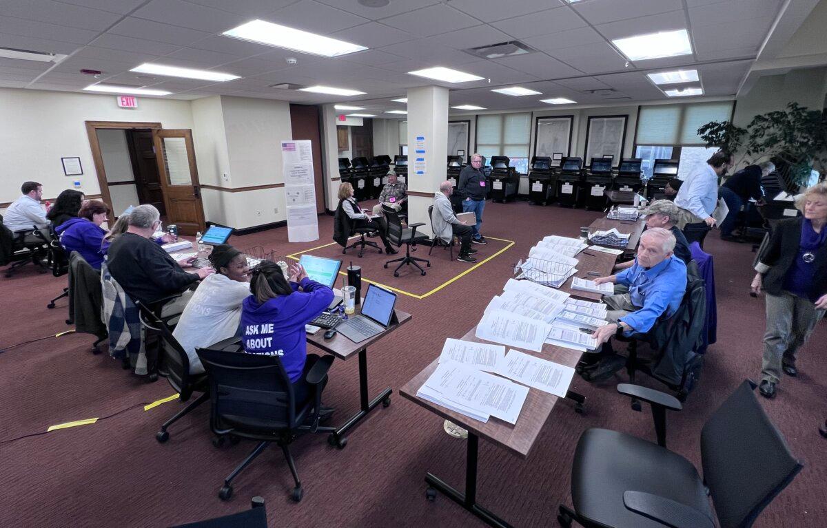Poll workers count absentee ballots as election observers look on at City Hall in Racine, Wis., on April 2, 2024. (Lawrence Wilson/The Epoch Times)