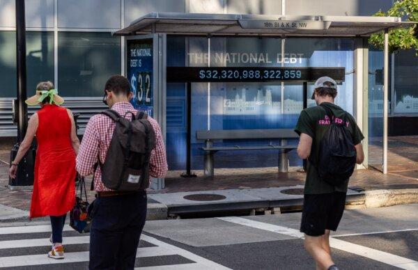 Pedestrians walk past an electronic billboard displaying the national debt at more than $32 trillion, in Washington on July 5, 2023. (Jemal Countess/Getty Images)