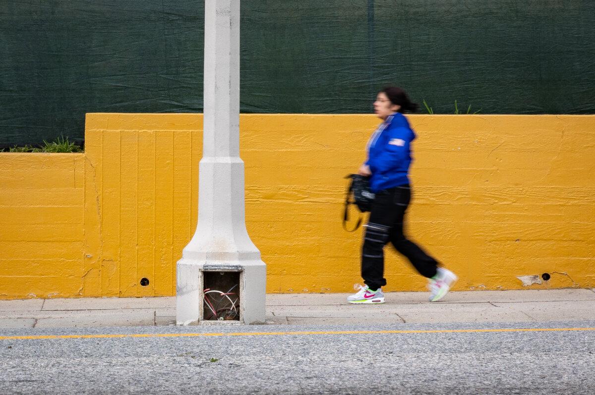 A woman walks past a streetlight subjected to wire theft in Los Angeles on April 4, 2024. (John Fredricks/The Epoch Times)