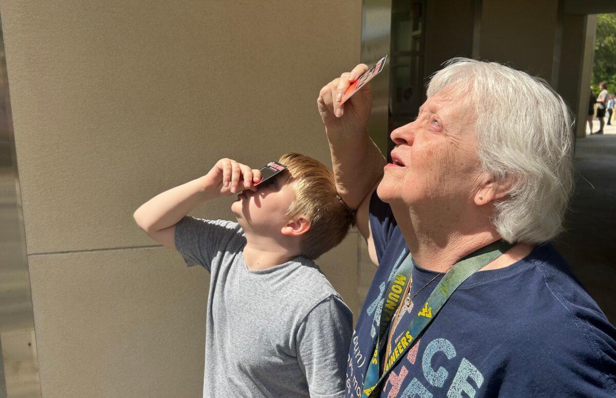 Brantley Wagers, 11, and his grandmother Debby Ashram view the eclipse outside the Kika Silva Pla Planetarium at Santa Fe College in Gainesville, Fla., on April 8, 2024. (Natasha Holt for The Epoch Times)