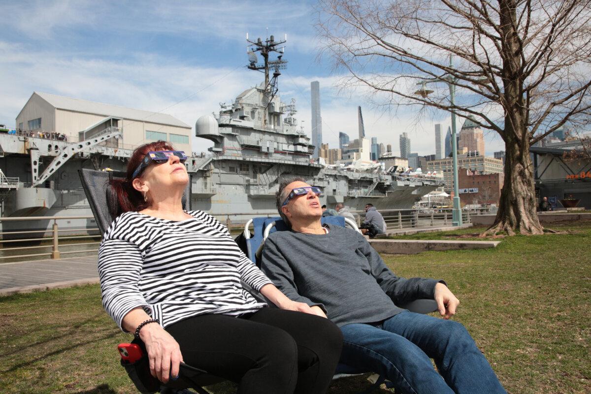 Holly and Antone, of Hell's Kitchen, settling in to watch the solar eclipse on Pier 84 at the Hudson River Park in New York on April 8, 2024. (Richard Moore/The Epoch Times)