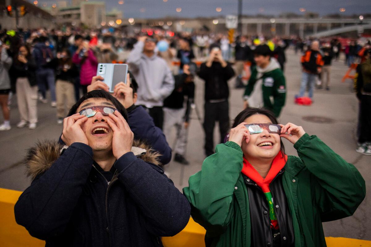Visitors use special glasses to watch the total solar eclipse from Niagara Falls, Ont., on April 8, 2024. (The Canadian Press/Aaron Lynett)