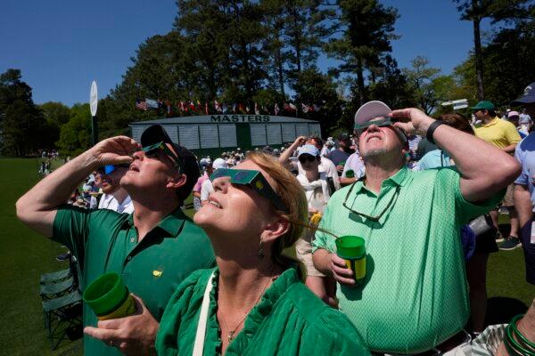 Patrons look up at a solar eclipse during a practice round for the Masters golf tournament in Augusta, Ga., on April 8, 2024. (George Walker IV/AP Photo)