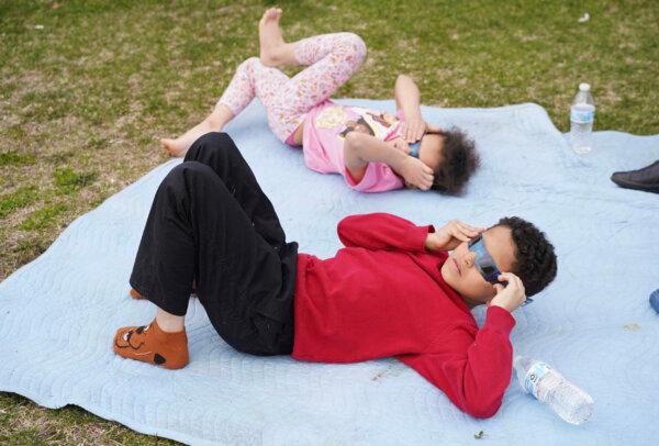 Children watch the eclipse at Riverside Park in Port Jervis, N.Y., on April 8, 2024. (Cara Ding/The Epoch Times)