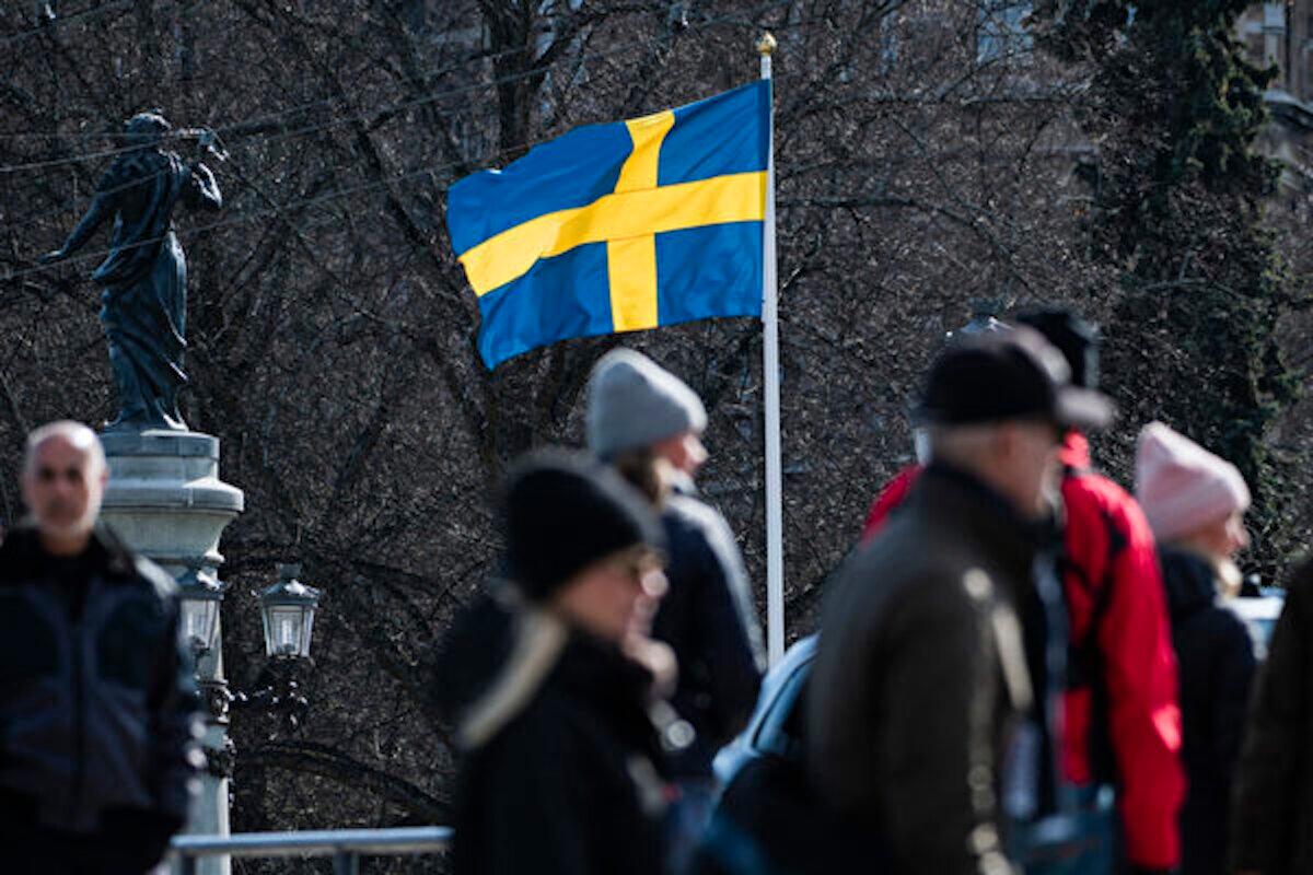 People walk past a Swedish flag in Stockholm on April 4, 2020. (Jonathan Nackstrand/AFP via Getty Images)
