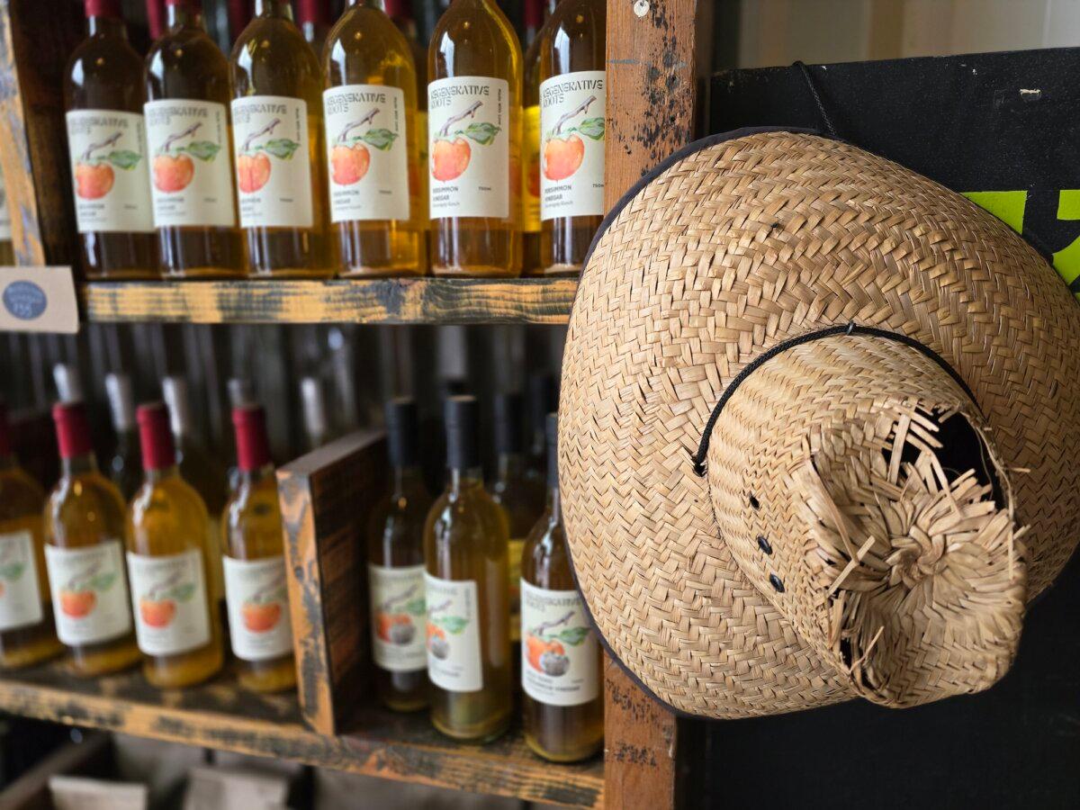 A gardening hat hangs on a hook next to bottles of persimmon vinegar at Sovereignty Farm in Bandera, Texas, on April 5, 2024. (Allan Stein/The Epoch Times)