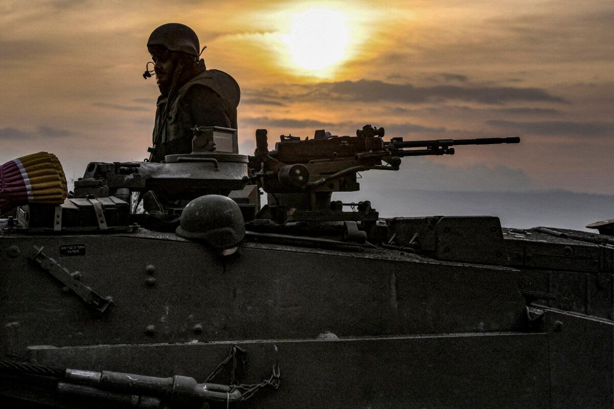 An Israeli army soldier sits in the hatch of the turret of a Merkava battle tank as a column of tanks is amassed in the upper Galilee in northern Israel near the border with Lebanon on Oct. 11, 2023. (JALAA MAREY/AFP via Getty Images)