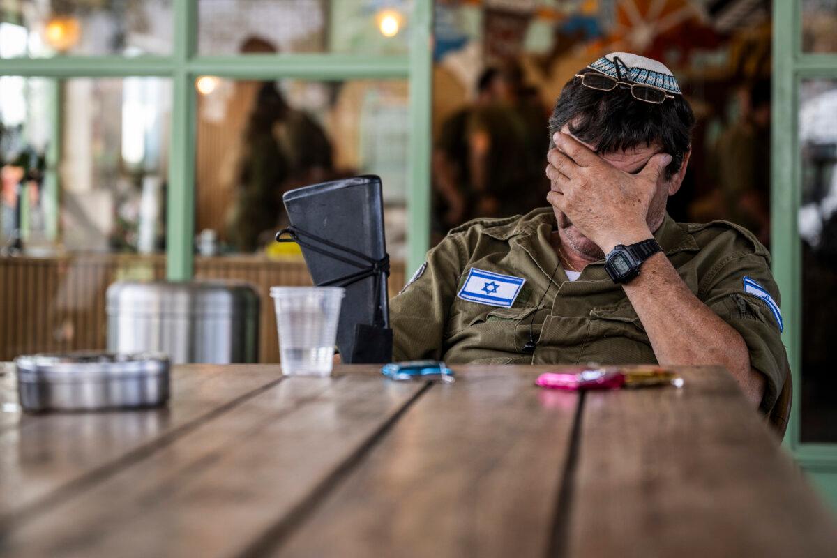 An IDF reservist rests his head in his hand at a cafe near the Gaza border in Urim, Israel, on Nov. 2, 2023. (Alexi J. Rosenfeld/Getty Images)