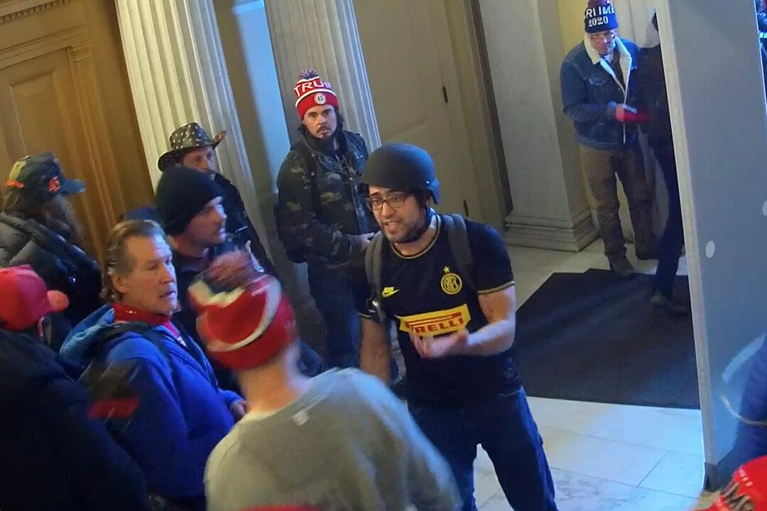 Zachary Alam (wearing the black helmet) is confronted by a man on his way out of the U.S. Capitol on Jan. 6, 2021. (U.S. Capitol Police/Screenshot via The Epoch Times)