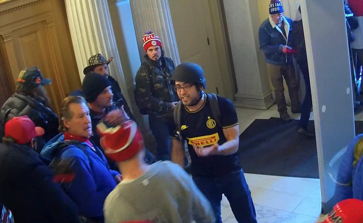 Zachary Alam (wearing a black helmet) is confronted by a man on his way out of the U.S. Capitol, on Jan. 6, 2021. (U.S. Capitol Police/Screenshot via The Epoch Times)