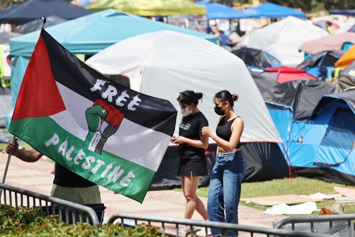 A protester carries a Palestinian flag at a pro-Palestinian encampment at the University of California–Los Angeles on April 30, 2024. (Mario Tama/Getty Images)