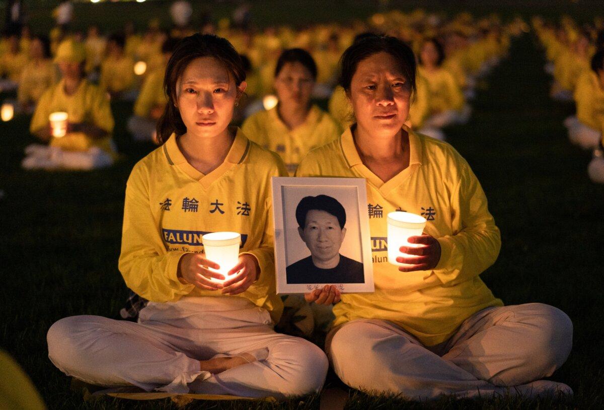 Daughter Li Xiaohua and mother Ju Reihjong attend a candlelight vigil to commemorate the victims of the 23-year-long persecution of Falun Gong in China, held at the Washington Monument on July 21, 2022. Ju holds a photo of her husband and Li's father, Li Delong, who died in the persecution.(Samira Bouaou/The Epoch Times)