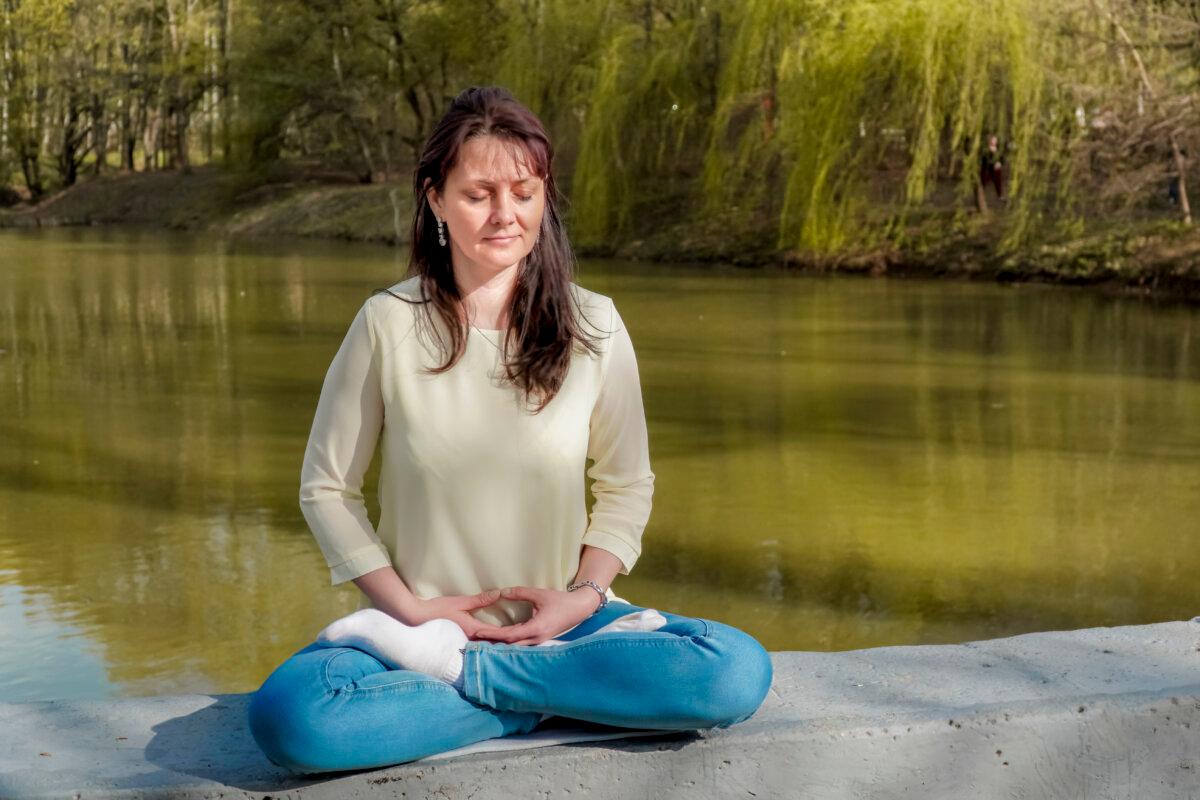 Natalya Minenkova does the Falun Gong meditation in Dendropark in Moscow, Russia, on July 5, 2022. (The Epoch Times)