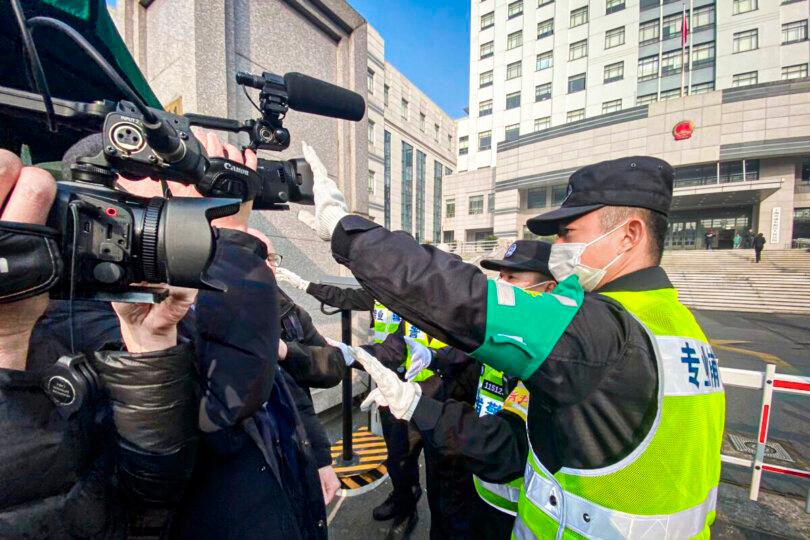 A policeman covers a camera to stop journalists from recording footage outside the Shanghai Pudong New District People's Court, where Chinese citizen journalist Zhang Zhan is set for trial in Shanghai, on Dec. 28, 2020. (Leo Ramirez/AFP via Getty Images)