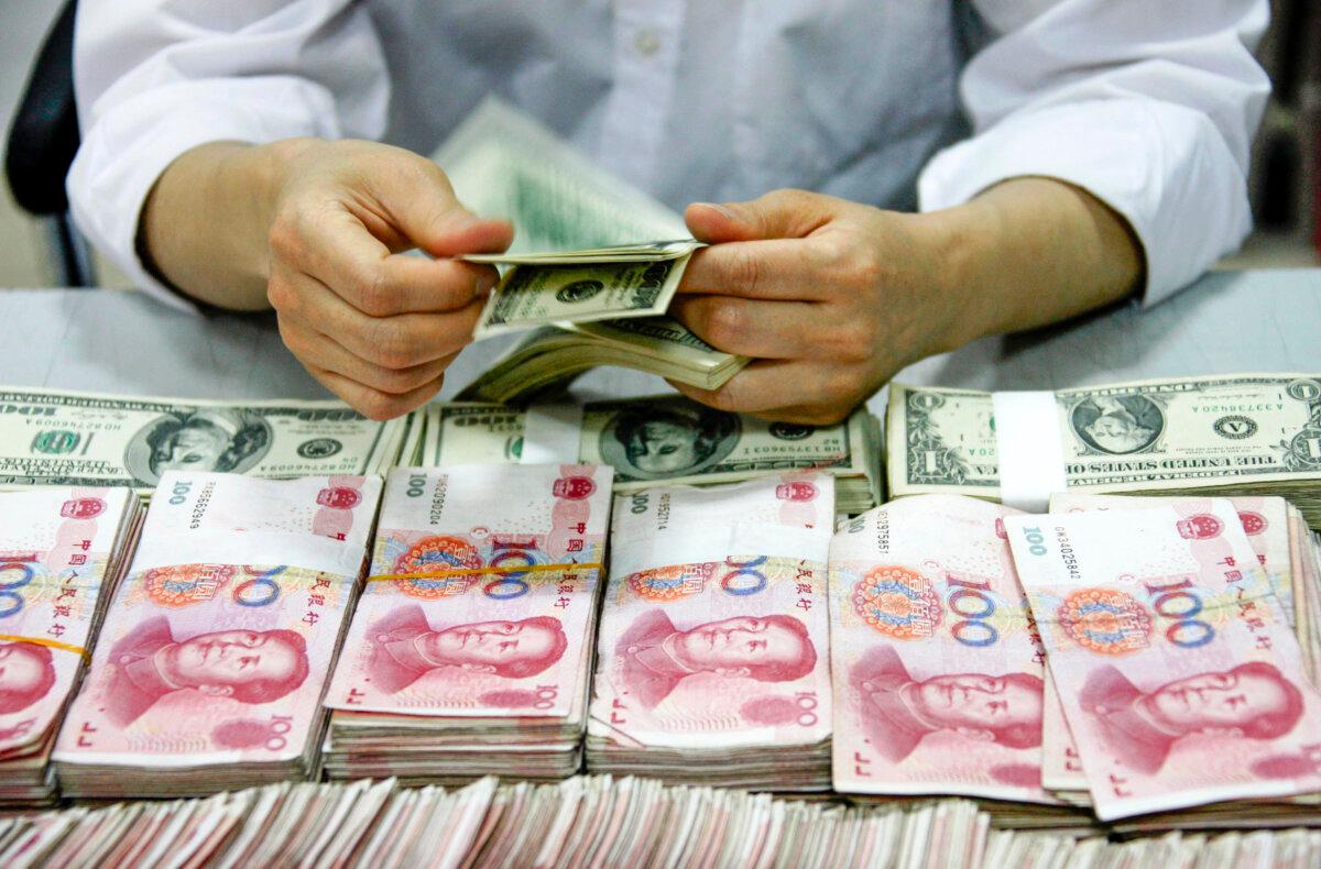 U.S. dollar notes being counted next to stacks of Chinese 100 yuan (RMB) bank notes at a bank in Huaibei, in eastern China's Anhui Province, on Sept. 24, 2013. (STR/AFP via Getty Images)