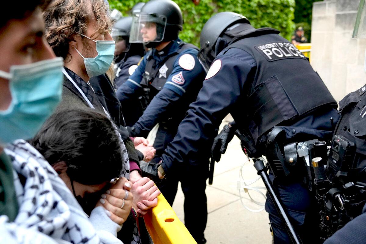A pro-Palestinian protester rests her head on her clasped hands while she stands before University of Chicago police officers in Chicago on May 7, 2024. (Charles Rex Arbogast/AP Photo)