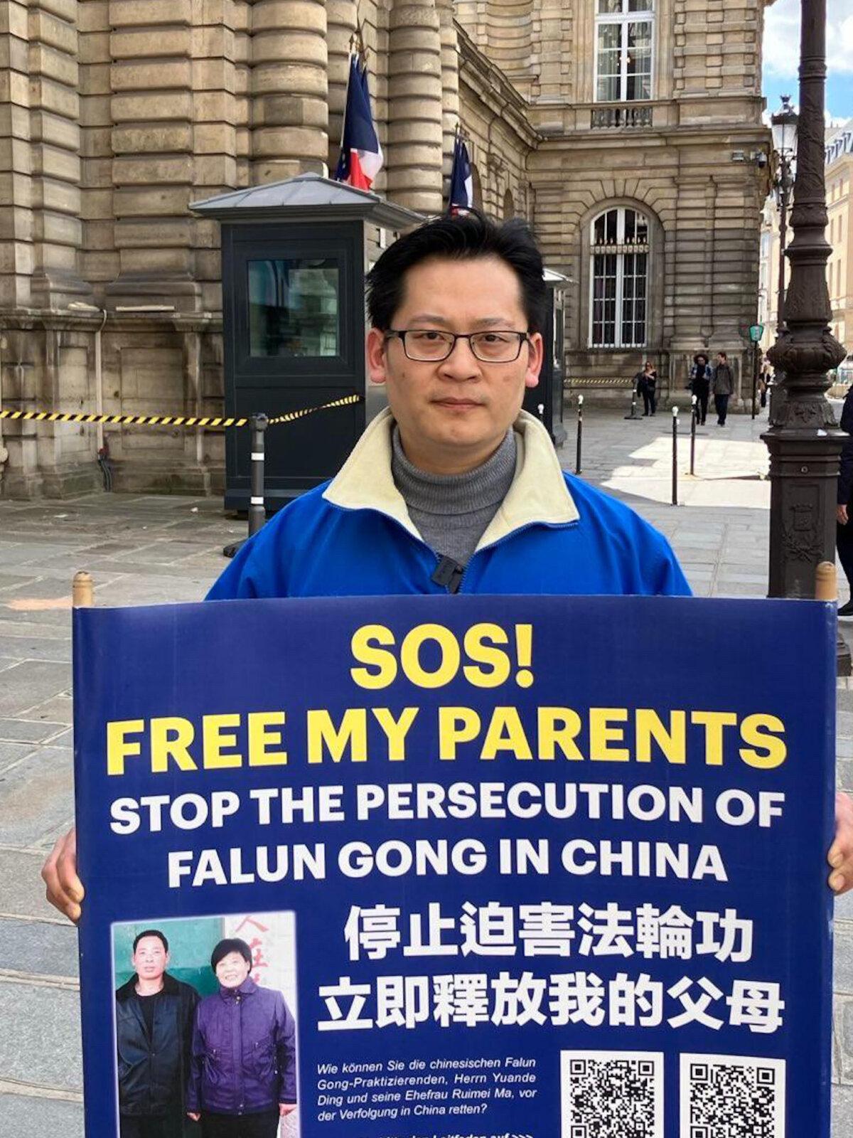 Ding Lebin holds a sign appealing for global attention to the persecution of his family in China, next to the Luxembourg Palace in Paris, on May 6, 2024. (David Vives/NTD)