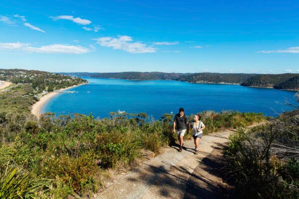 Couple enjoying a scenic coastal hike on the Barrenjoey Lighthouse Walk in Palm Beach, Sydney. (Courtesy of Destination NSW)