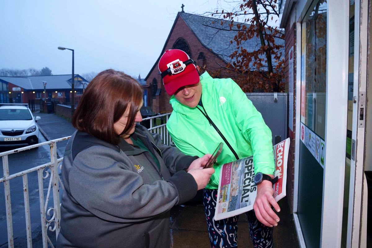 Ms. Ryvar has her picture taken with her running watch and the day's local newspaper, a daily ritual, to prove she has completed her daily half marathon. (Jon Super/AP Photo)