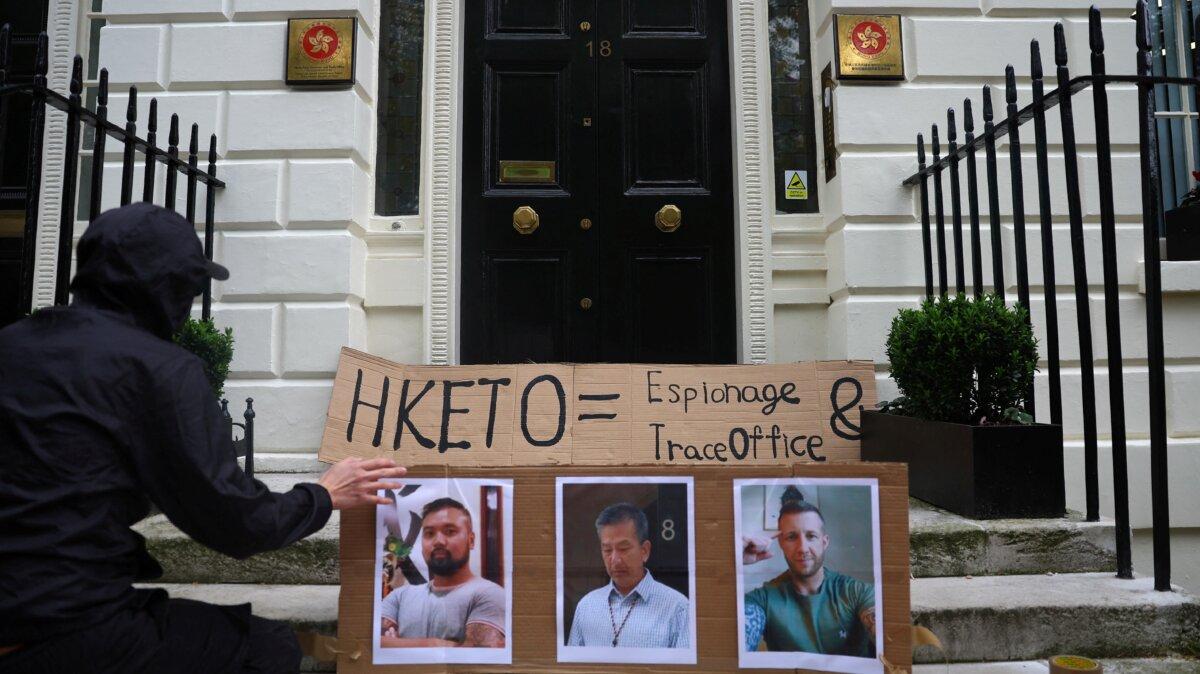 A protester places photos of three men charged with assisting Hong Kong's foreign intelligence service in the UK on the door of the Hong Kong Economic and Trade Office, in London on May 14, 2024. (Toby Melville/Reuters)