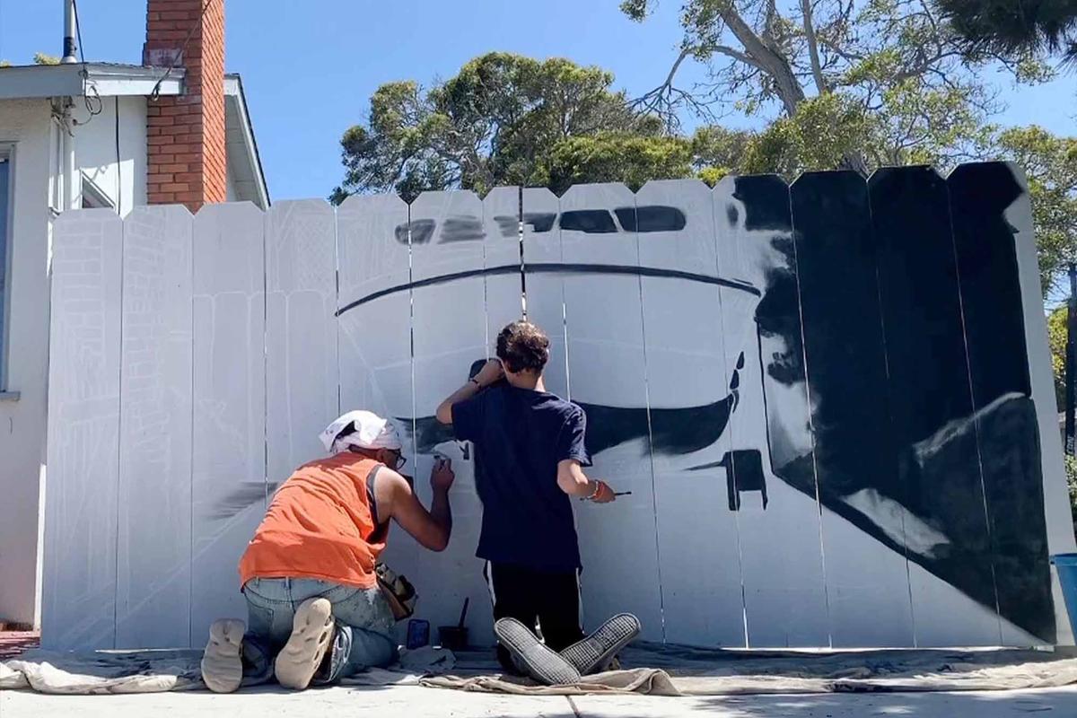 Boat owner Etienne Constable hired Hanif Panni to paint a mural of his boat on his fence mandated by the city to enclose his boat. (Courtesy of <a href=