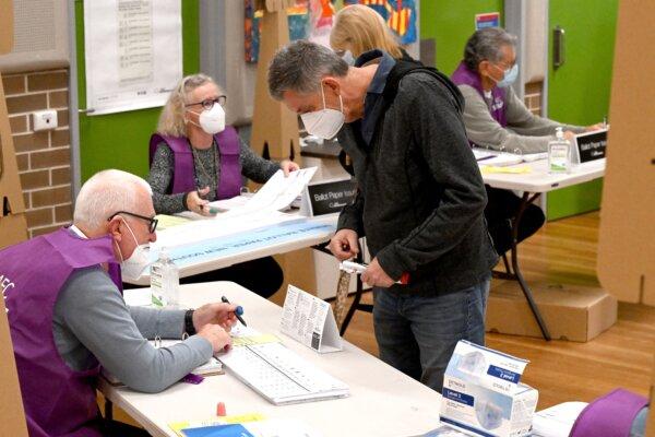 A polling agent issues ballot papers to a voter at a polling station in Sydney, Australia, on May 21, 2022. (Saeed Khan/AFP via Getty Images)