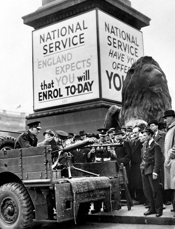 People watching soldiers demonstrating a Vickers machine gun and a range finder underneath a poster for national service in Trafalgar Square, London, on Sept. 5, 1939. (PA wire)