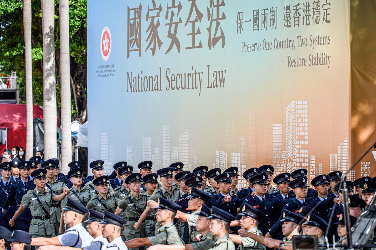 Attendees from various forces march next to a banner promoting the new national security law at the end of a flag-raising ceremony to mark the 23rd anniversary of Hong Kong's handover from the UK in Hong Kong on July 1, 2020. (Anthony Wallace/AFP via Getty Images)