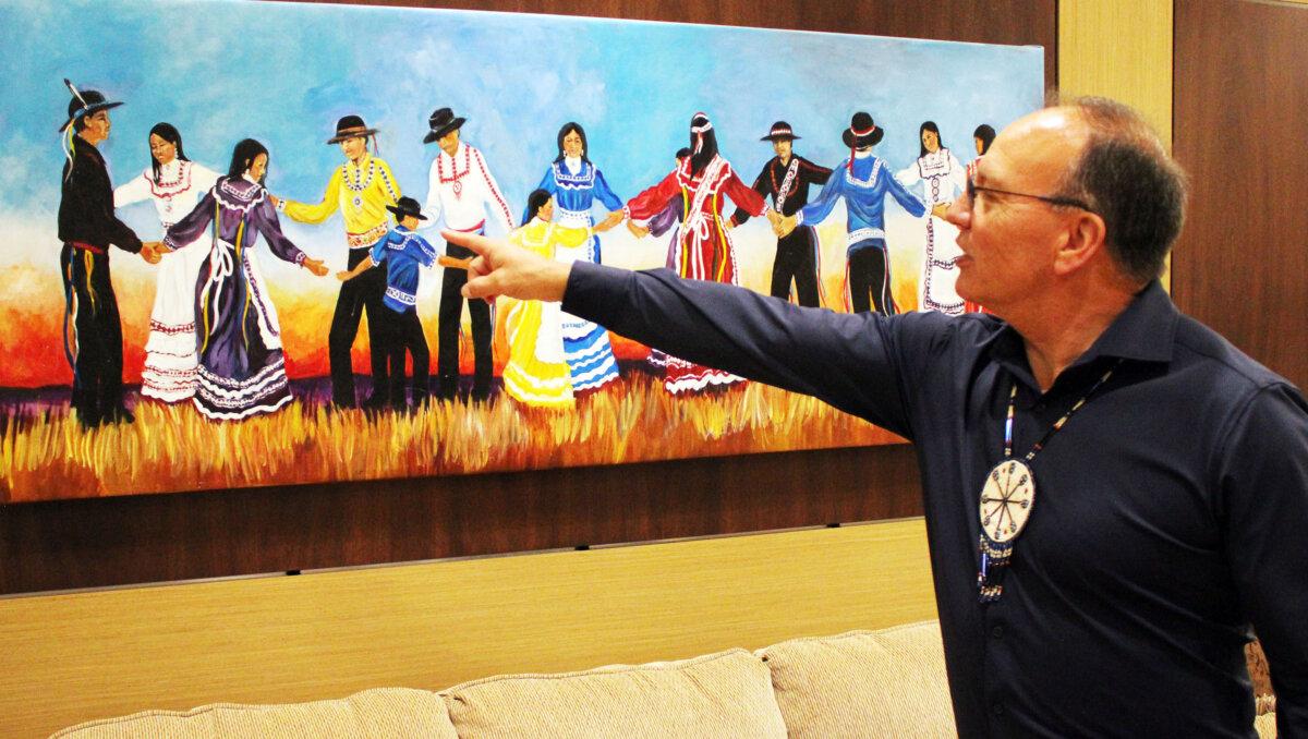 Choctaw Chief Gary Batton points out details in a painting of tribal dancers by artist Janie Semple Umsted in the Choctaw Tribal Headquarters in Durant, Okla., on May 16, 2024. (Michael Clements/The Epoch Times)