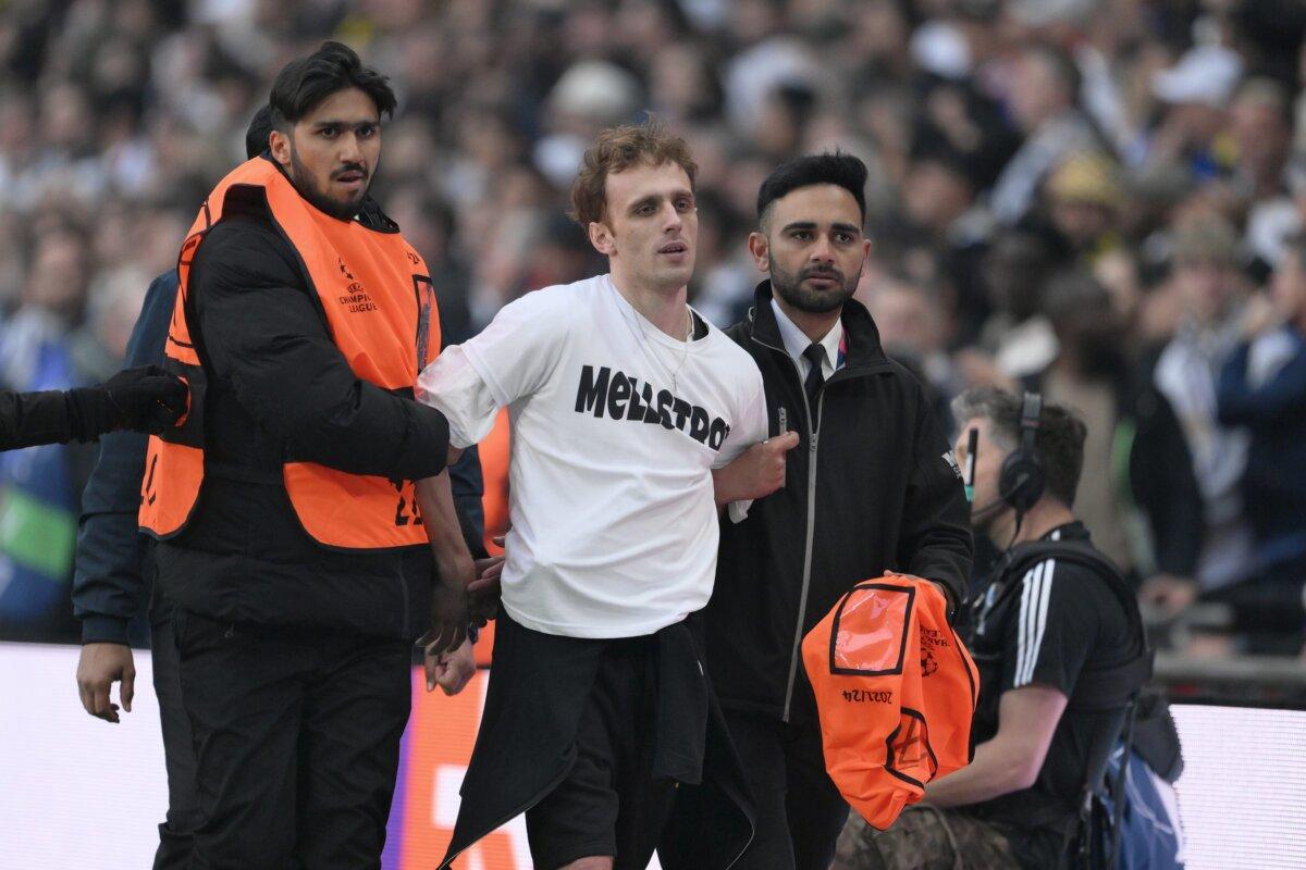 A pitch invader, wearing a T-shirt which reads "MELLSTROY," is stopped by members of security during the UEFA Champions League 2023/24 Final match between Borussia Dortmund and Real Madrid CF at Wembley Stadium in London on June 1, 2024. (David Ramos/Getty Images)