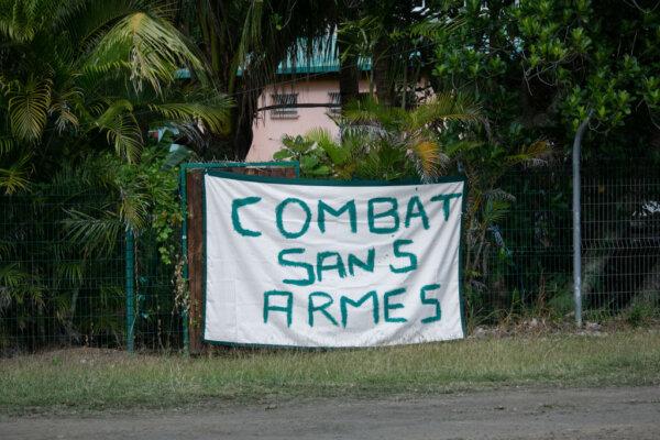 This photograph shows a slogan which reads "unarmed combat" in the Jacarandas district of Dumbea, France's Pacific territory of New Caledonia, on June 2, 2024. (Delphine Mayeur/AFP via Getty Images)