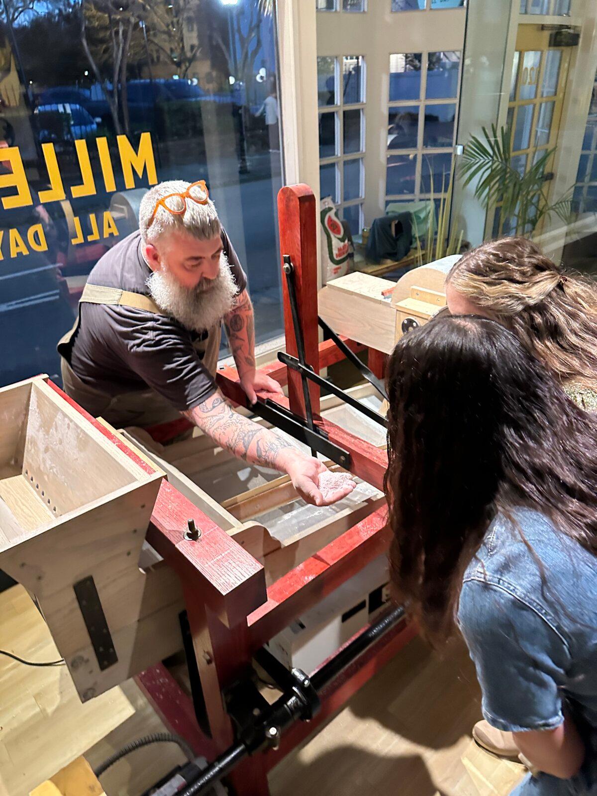 Mr. Johnsman demonstrates an old 1850's separator, which separates the milled corn into different sizes, that he restored with his father. They are on display in the Millers All Day restaurant in downtown Charleston, S.C. (Bard Prochaska)