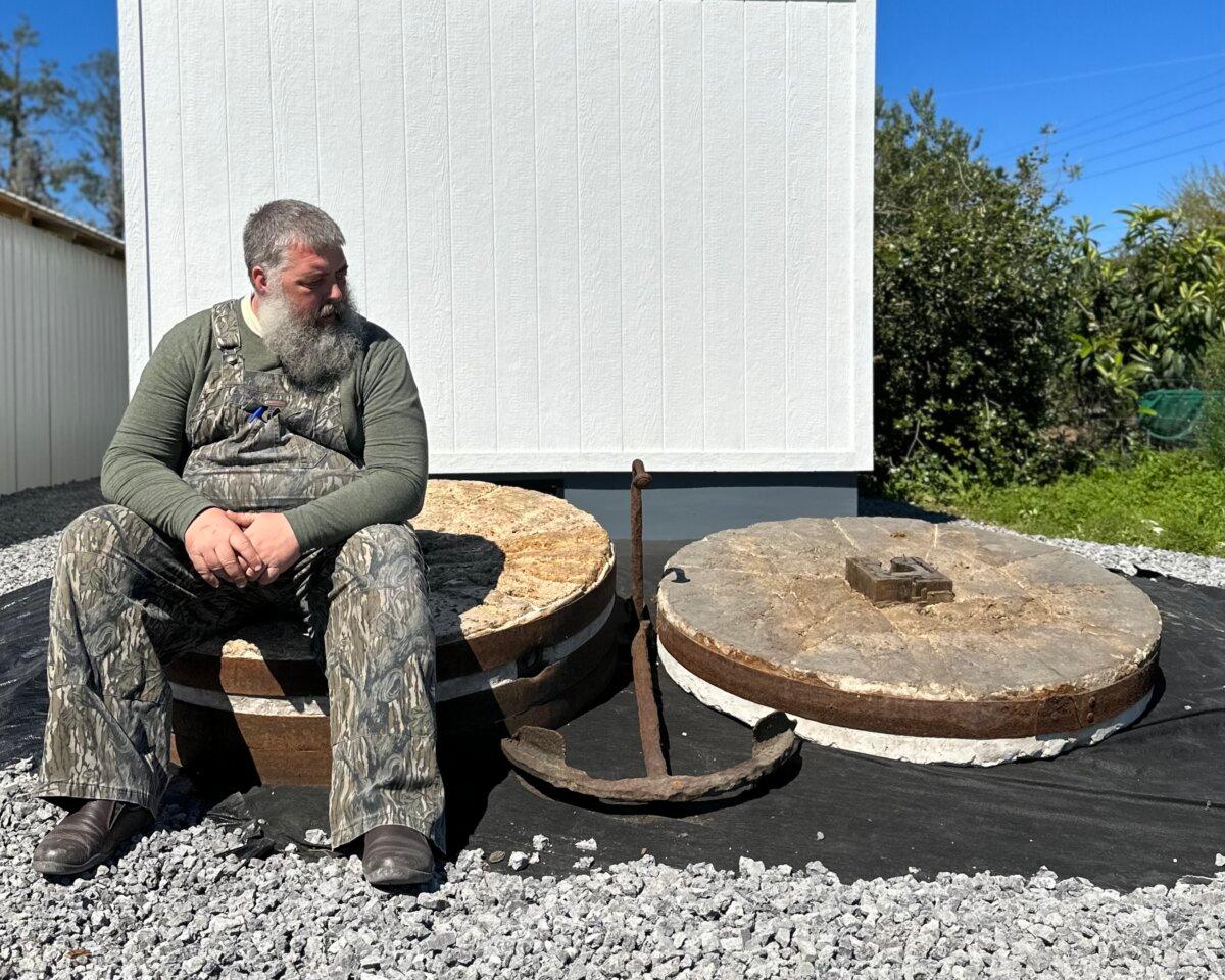 Greg Johnsman sits on large mill stones from an old water mill, which sit in front of the Marsh Hen Mill office on Edisto Island, S.C. (Bard Prochaska)