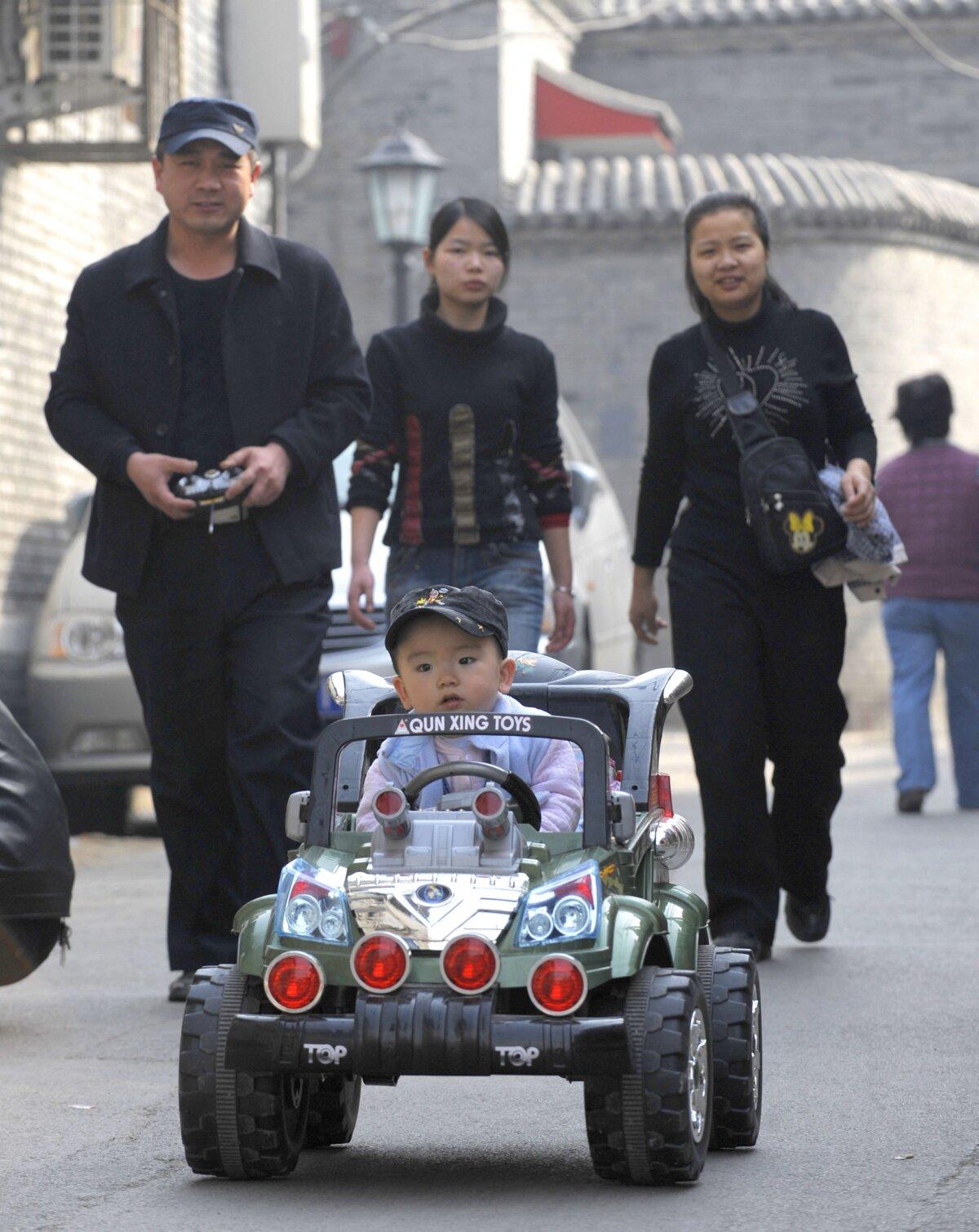 A baby boy sits in a luxury toy car, riding next to his family along a street in Beijing on Oct. 21, 2011. (Liu Jin /AFP via Getty Images)