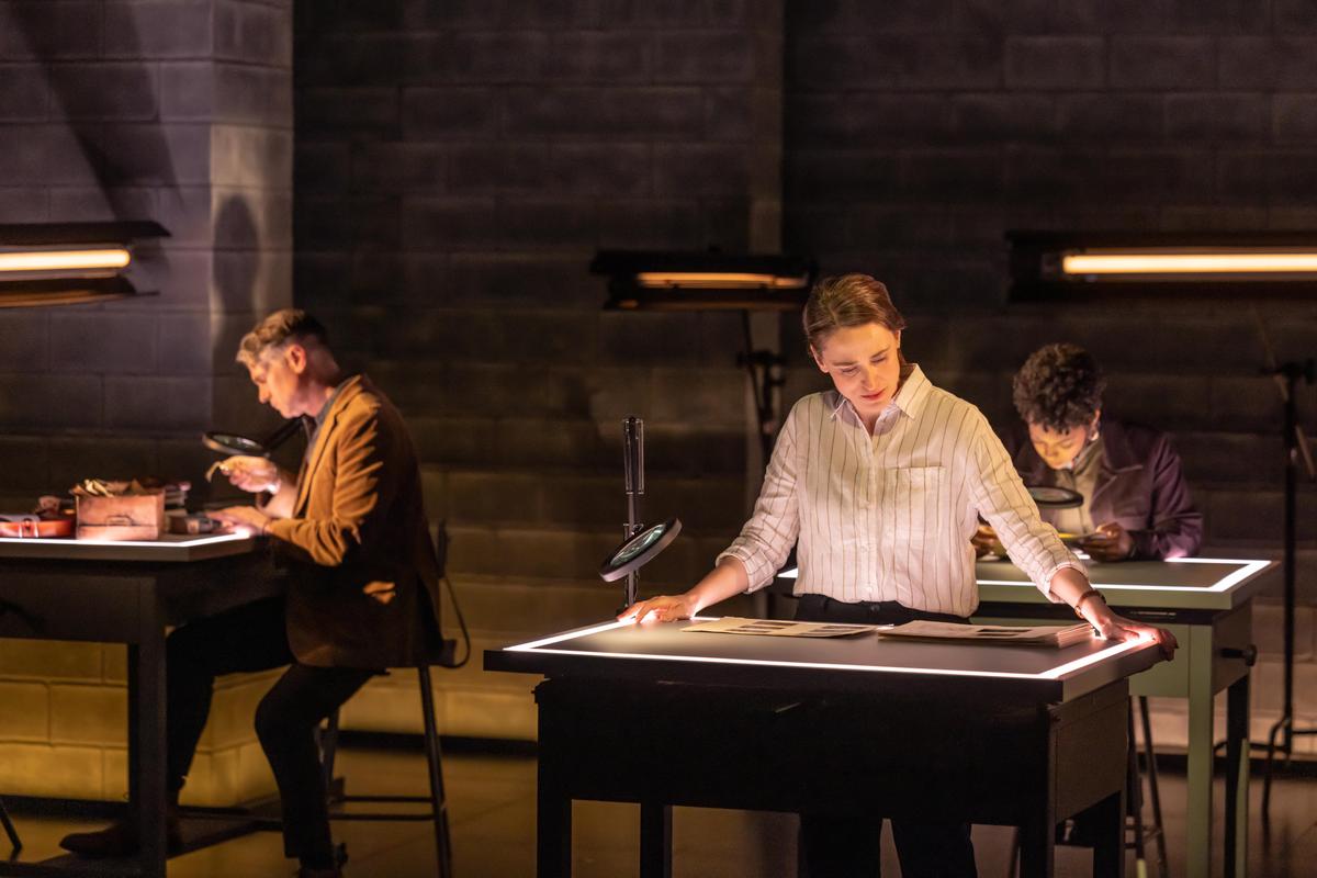 Rebecca Erbelding (Elizabeth Stahlmann) examines the photographs, in "Here There Are Blueberries." (Matthew Murphy)