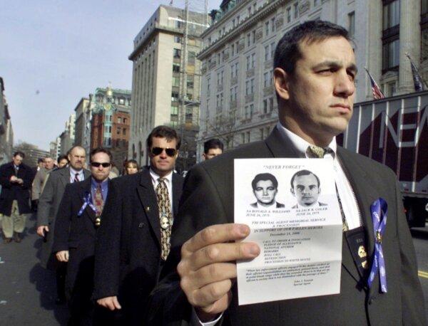 An unidentified FBI agent, one of the nearly 500 current and retired FBI agents protesting clemency for Leonard Peltier, marches toward the White House on Dec. 15, 2000, holding an image of two FBI agents, Ron Williams and Jack Coler. (Hillery Smith Garrison/AP Photo)